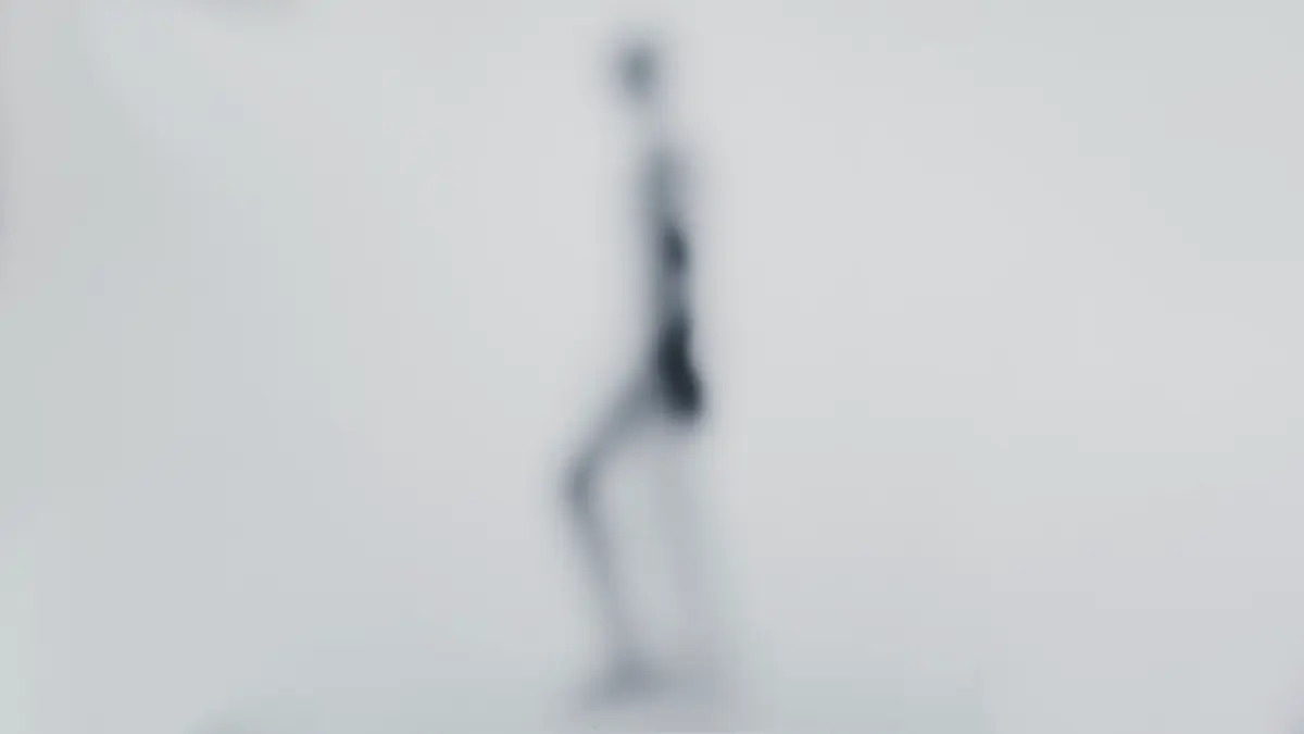 A screenshot from the Figure AI teaser video, showing the silhouette of a new humanoid robot walking behind a frosted glass effect.