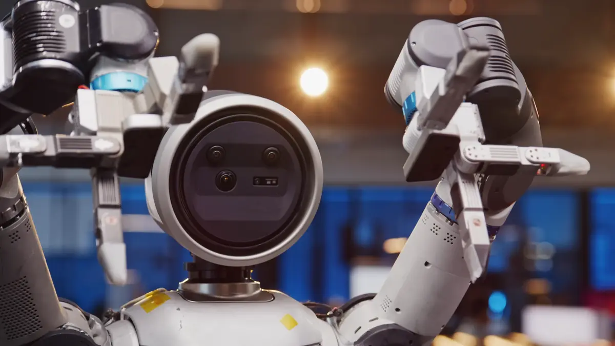 The Boston Dynamics Atlas robot holds its hands up, with the fingers of one hand curled forward and the fingers of the other bent backward to demonstrate their full range of motion.