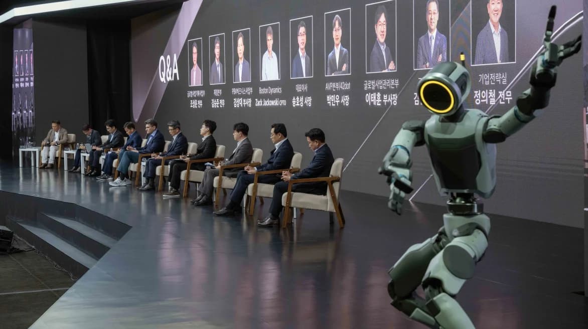 A row of Kia and Boston Dynamics executives sitting on a stage for a Q&A session  at the 2026 Kia CEO Investor Day, with an Atlas humanoid robot in the foreground.