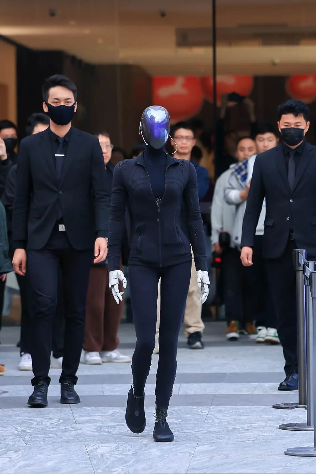 Xpeng Iron humanoid robot walking through a crowd flanked by security.