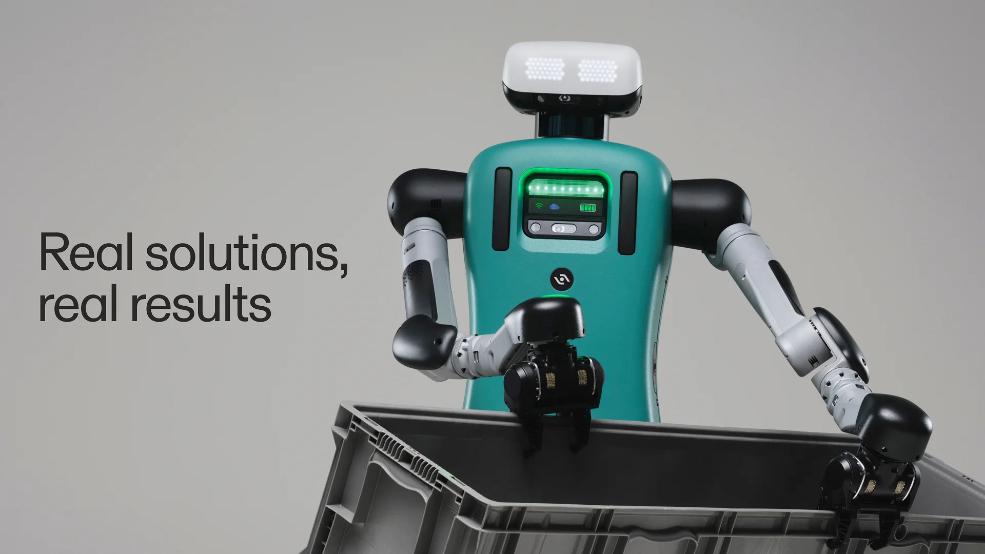 A close-up of the Digit robot, featuring a teal torso with the new black Agility symbol on its chest. The robot is shown grasping a grey industrial tote, with the text "Real solutions, real results" displayed on the left.
