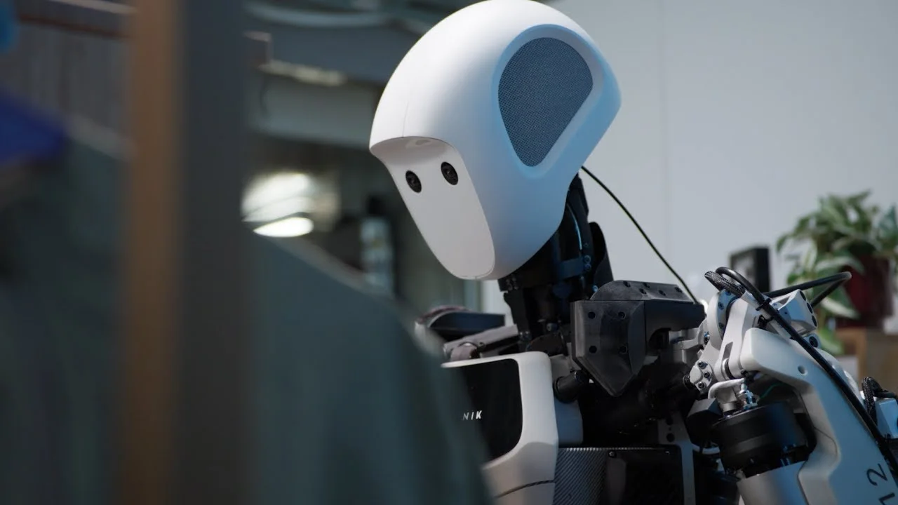 A close-up photograph of the head and upper torso of Apptronik's white humanoid robot, Apollo, with its camera sensors visible on its face.