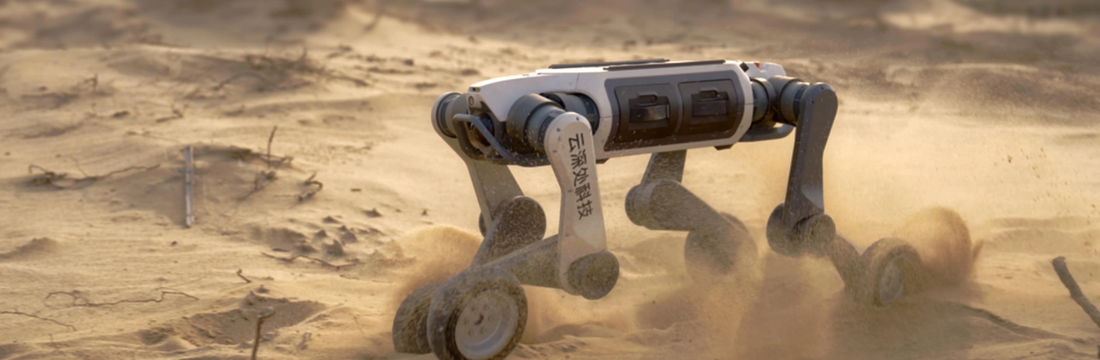 The Deep Robotics Lynx M20 wheeled-legged robot driving rapidly through sand, kicking up dust.