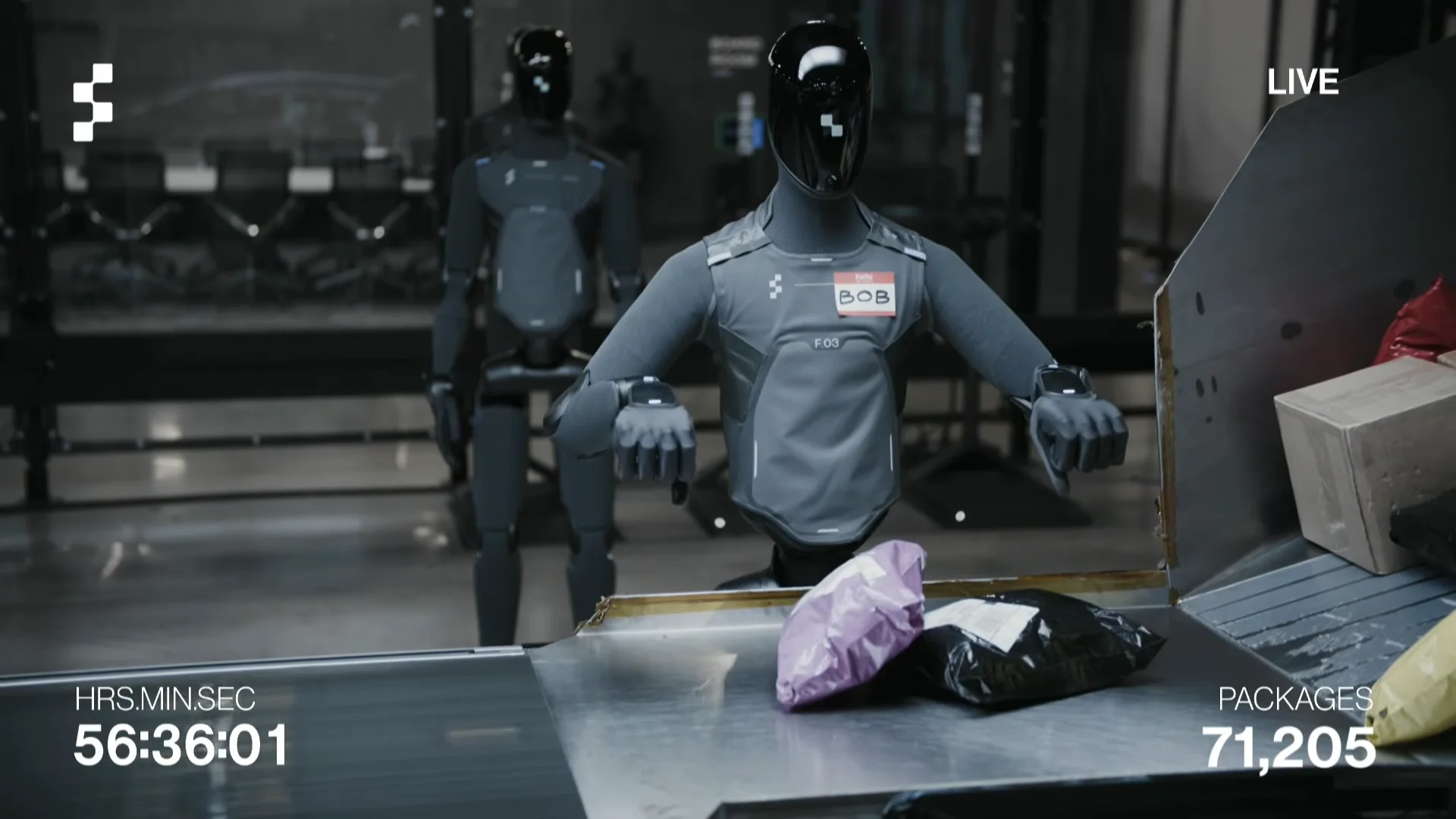 A screenshot from the Figure AI live video feed showing the charcoal-grey Figure 03 humanoid robot named 'Bob' pausing at a metal conveyor belt. Behind Bob, a second identical humanoid robot stands ready to step forward in a dimly lit facility background. In-video overlays at the bottom indicate a runtime of 56:36:01 and a package count of 71,205.