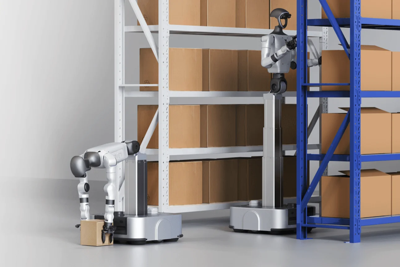 wo Unitree G1-D robots operating in a warehouse setting; one robot is lowered to pick up a package from the floor, while the second has extended its telescoping torso to place a box on a high shelf.