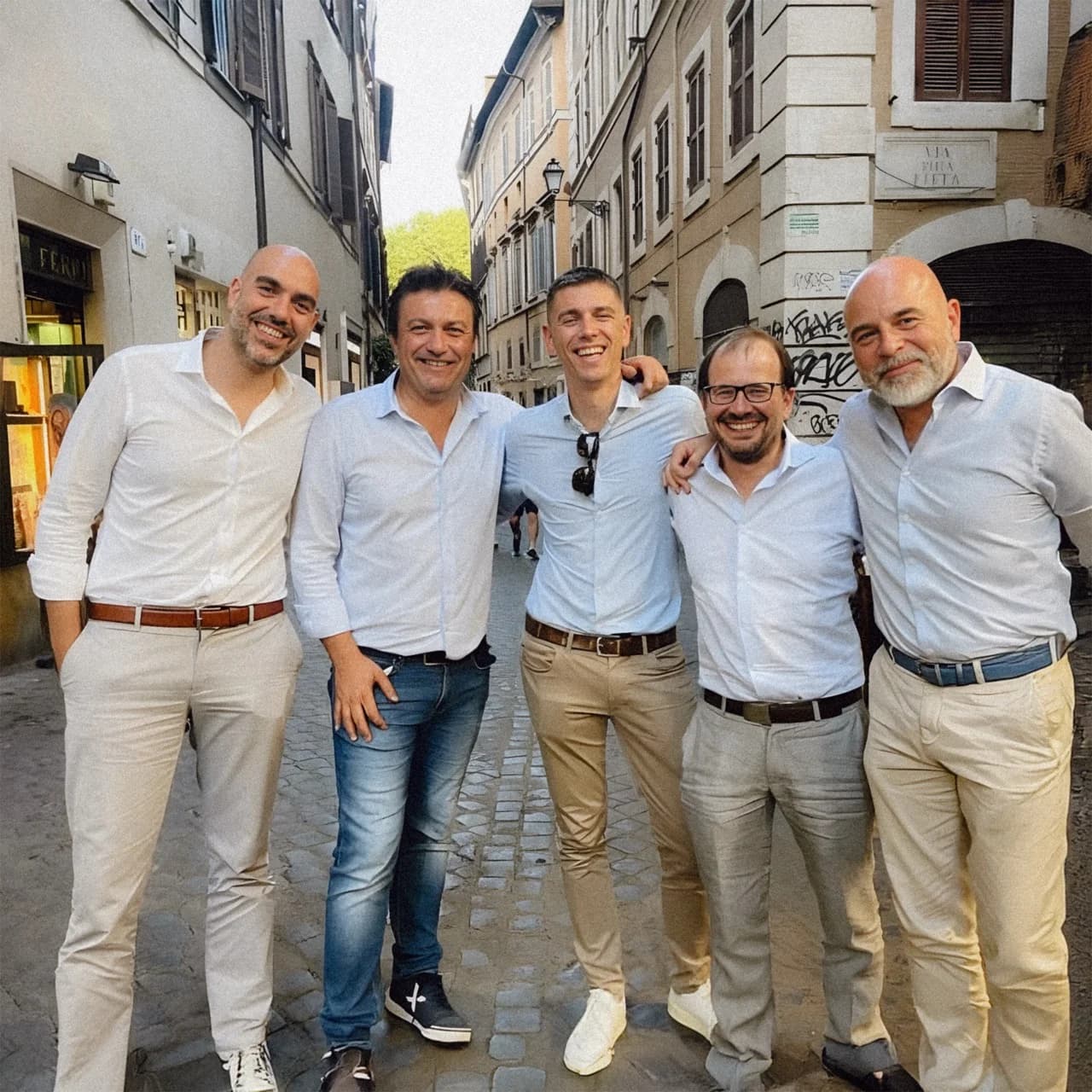 The five founders of Generative Bionics standing arm-in-arm on a cobblestone street in Italy.