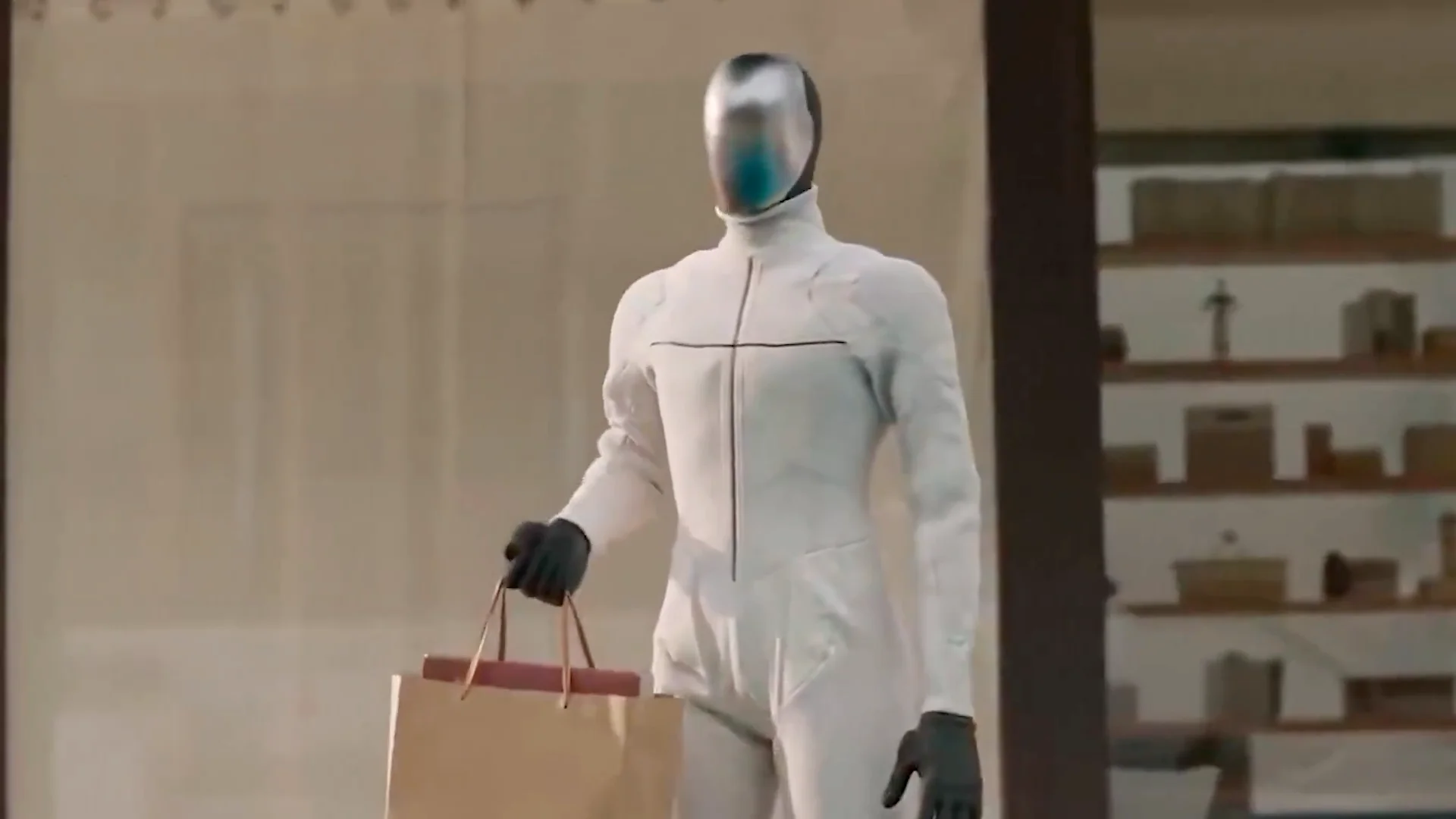 A KAI humanoid robot with a sleek silver faceplate and a white textured body suit walks forward while carrying two brown paper shopping bags in its right hand. The background shows a blurred domestic or retail setting with wooden shelving.