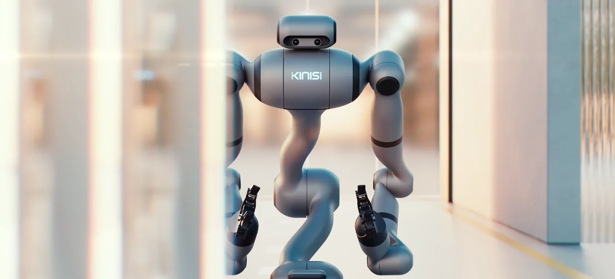 A medium shot of the Kinisi 01 robot, featuring a sleek, silver-grey humanoid upper body. The robot has a head with two camera lenses resembling eyes, a torso with the "KINISI" logo, and articulated arms with grippers. The body connects to the lower chassis with a curved, serpentine structure.