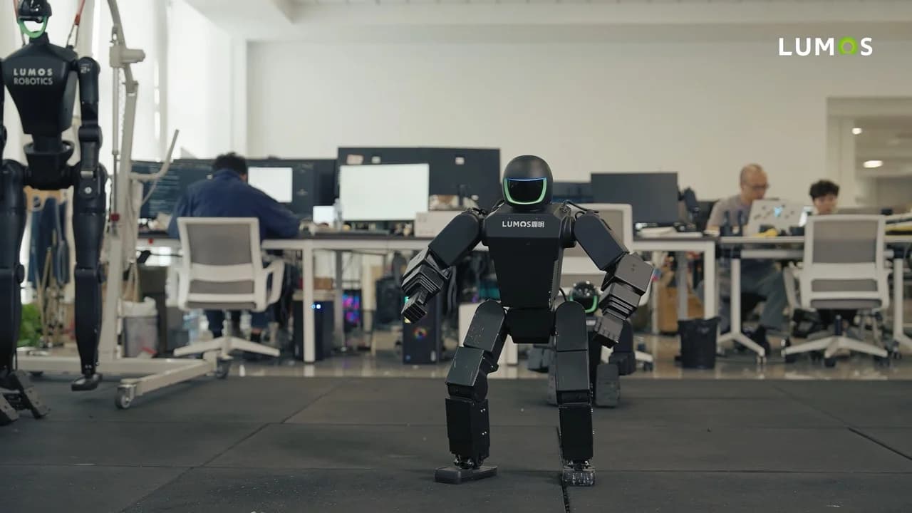 The LUMOS NIX humanoid robot standing upright in a robotics development laboratory with engineers working at desks in the background.