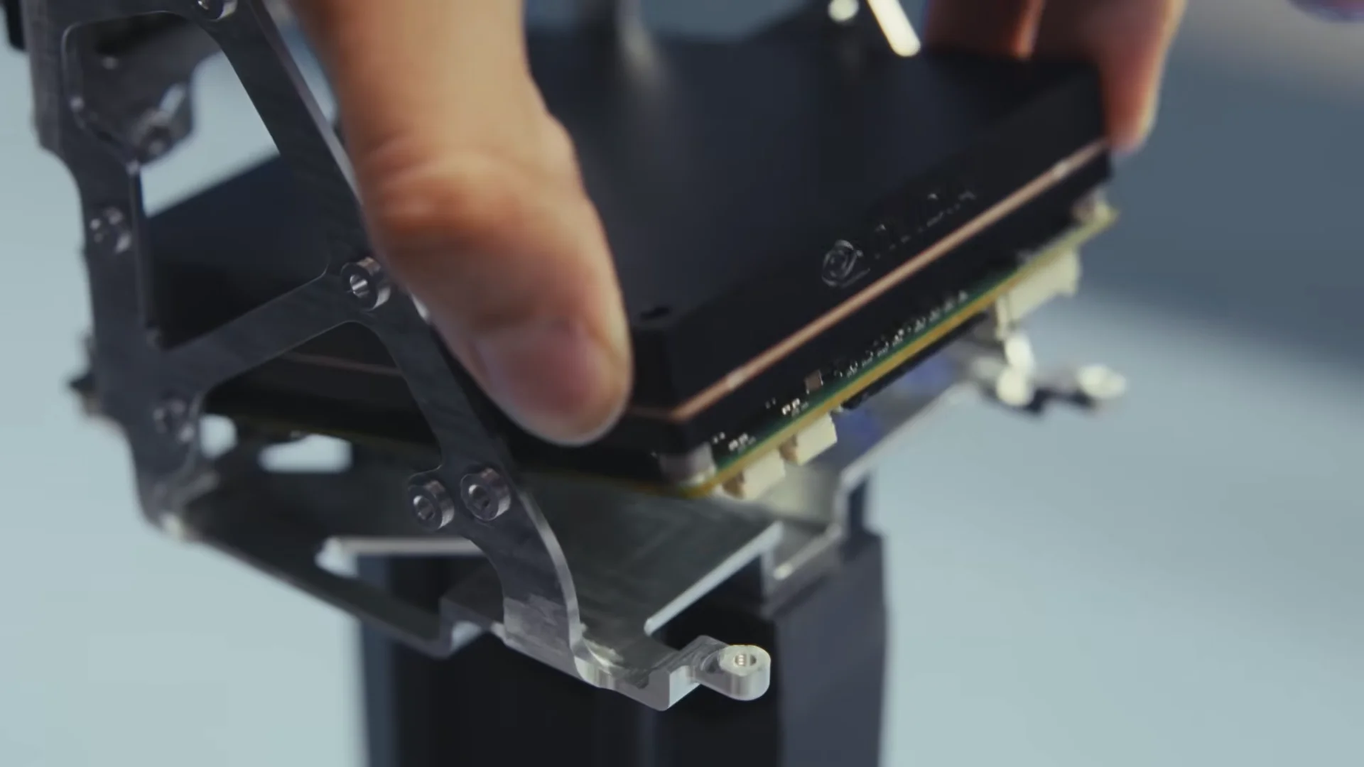 A technician’s hands installing a black electronic module with the NVIDIA logo into a silver metallic frame inside a robot’s chassis.