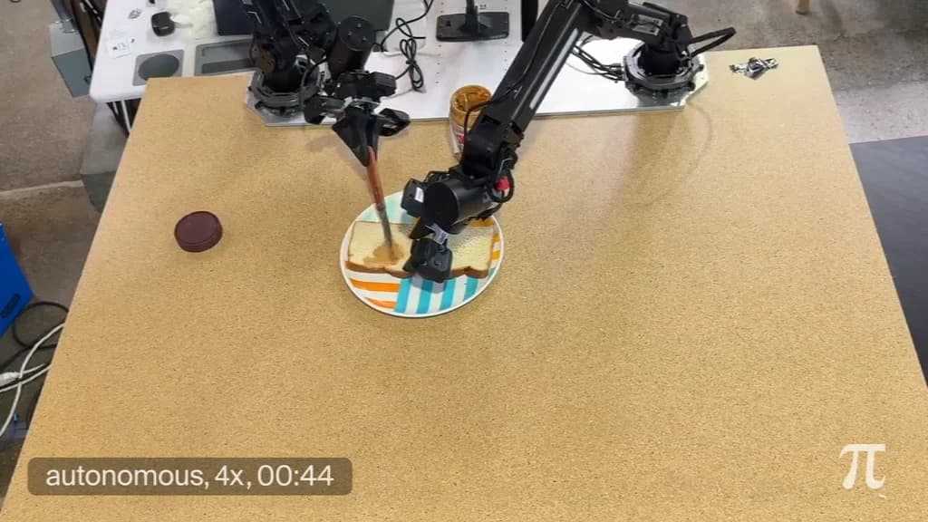 An overhead view of two robotic arms on a wooden table. One arm uses a knife to spread peanut butter on a slice of bread on a striped plate, while the other holds the bread steady.