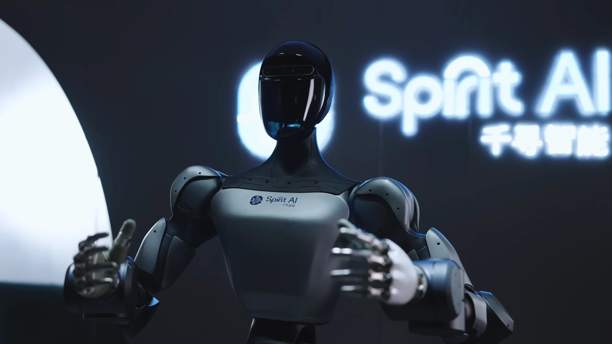A studio shot of the upper body of the Spirit AI "Moz" humanoid robot. The robot features a sleek, glossy black head with a visor-like face, a silver torso displaying the Spirit AI logo, and highly articulated mechanical hands.