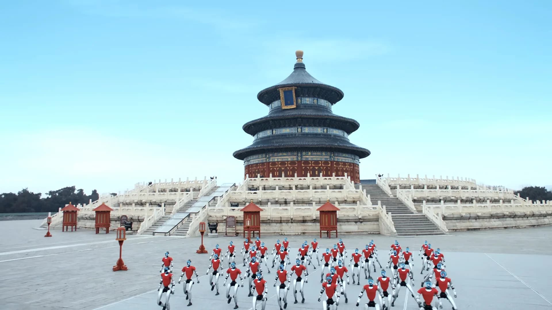 A wide-angle, high-perspective shot of dozens of Unitree G1 humanoid robots standing in a precise grid formation on the paved square leading to the Hall of Prayer for Good Harvests. The robots wear red vests and have glowing blue faceplates.