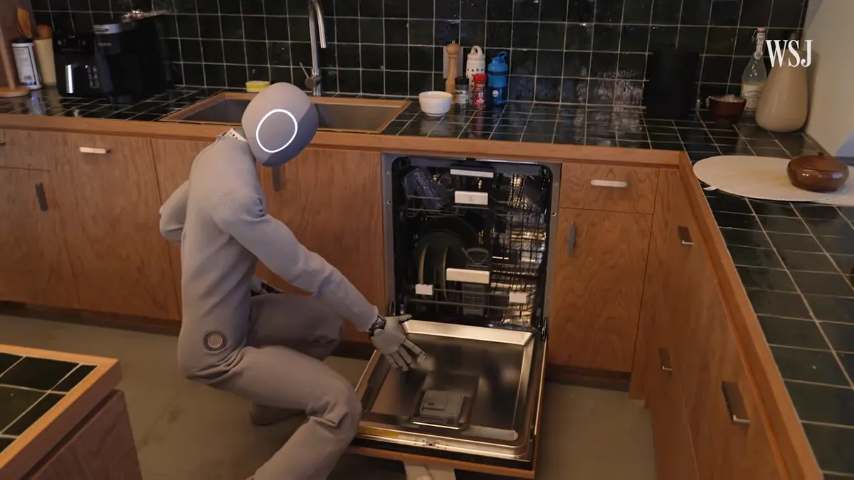 A NEO Gamma humanoid robot crouches down to close a dishwasher