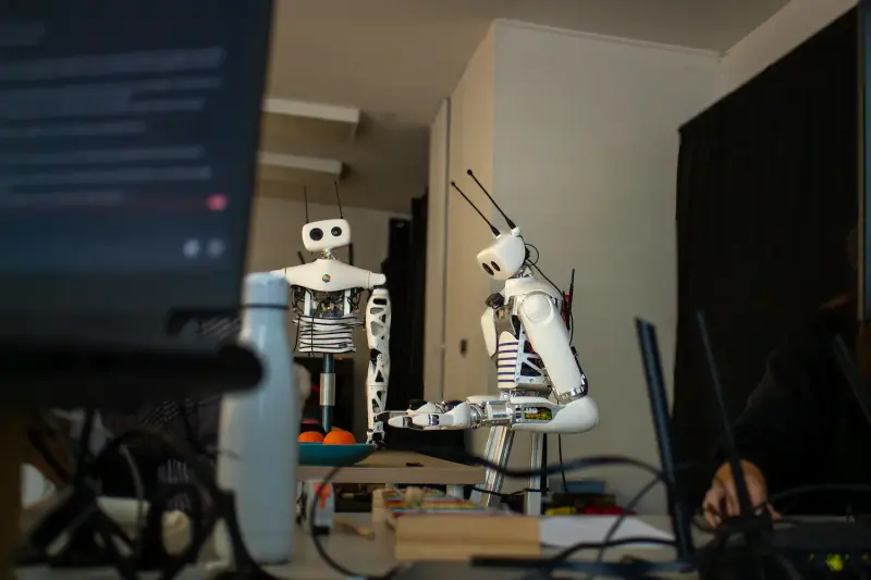 Humanoid Robots developed by Pollen Robotics standing at a table