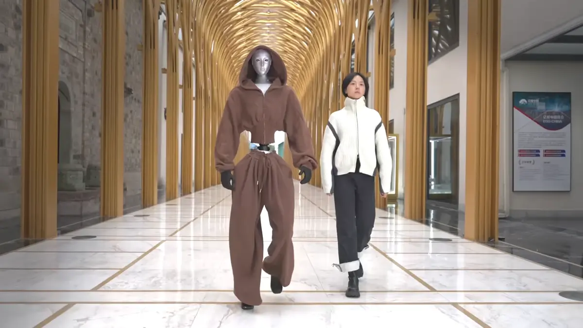 Unitree H2 humanoid robot walking down a hallway dressed in clothes