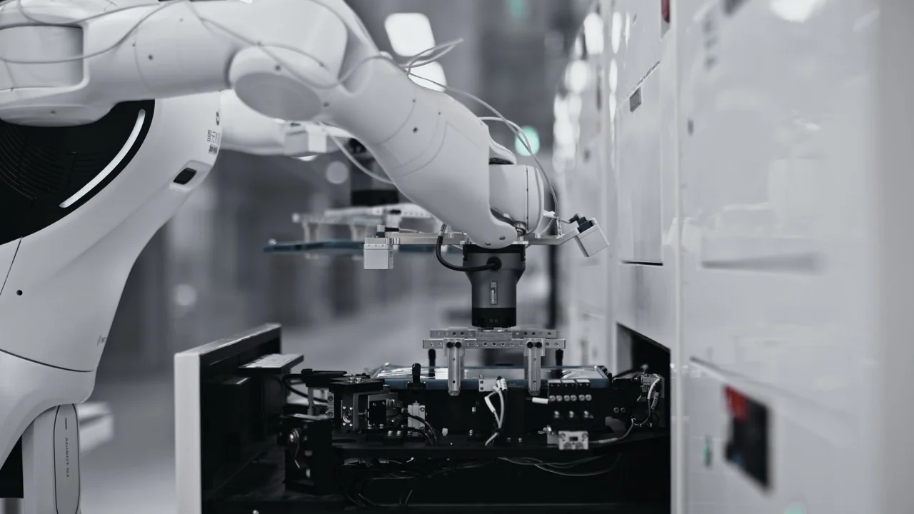 Close-up of the G2’s robotic wrist and gripper assembly precisely lowering a tablet into a mechanical testing slot.