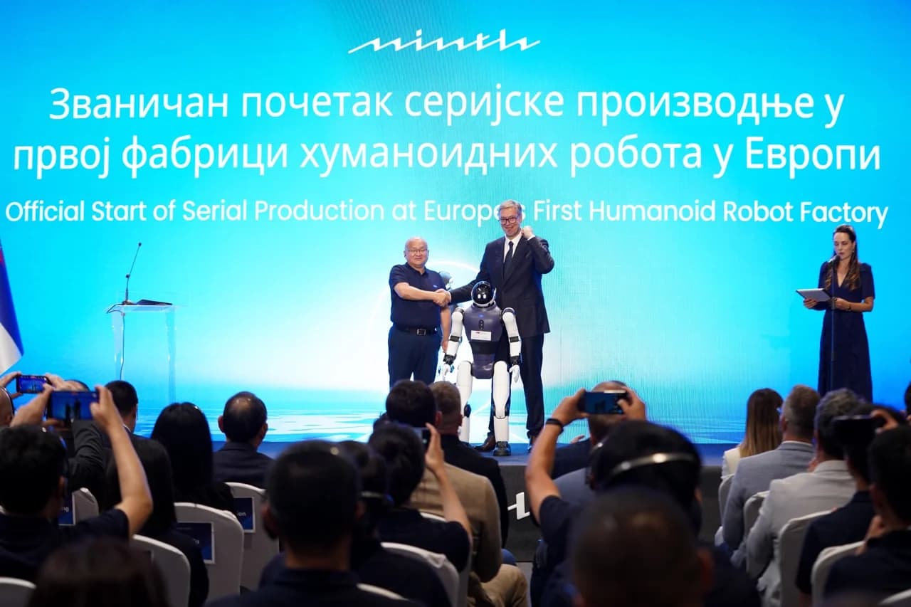 Minth Group founder Chin Jong Hwa shakes hands with Serbian President Aleksandar Vučić behind an AGIBOT humanoid robot on a stage in front of a blue screen reading 'Official Start of Serial Production at Europe's First Humanoid Robot Factory'.