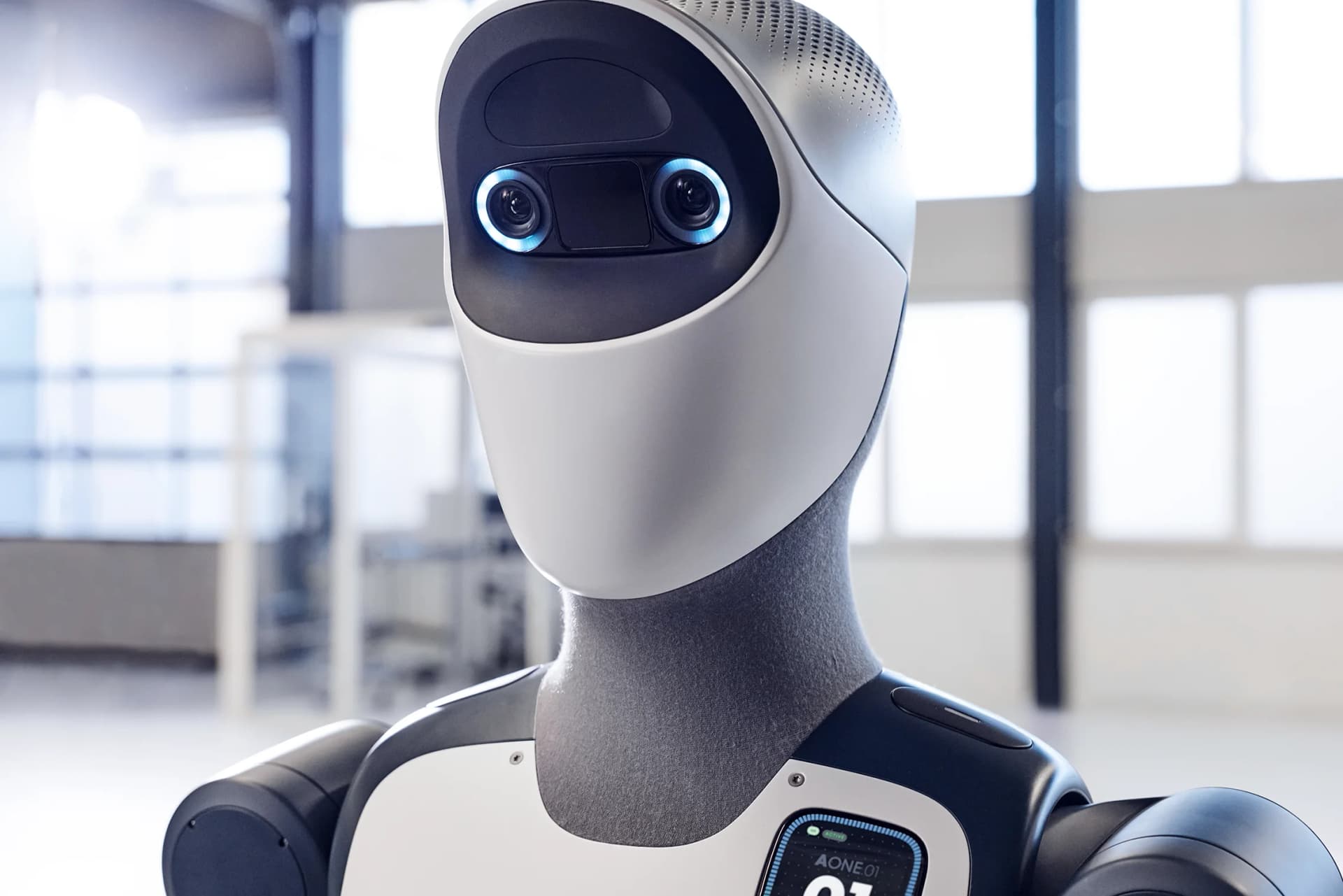 A close-up of the Agile ONE robot's head, showing a smooth white faceplate, two camera lenses surrounded by blue illuminated rings, and a forehead-mounted sensor array.