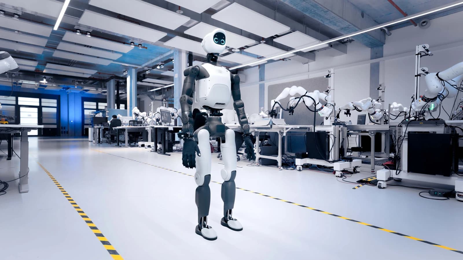 Agile ONE SN humanoid standing in a robotics laboratory lined with robot arms.