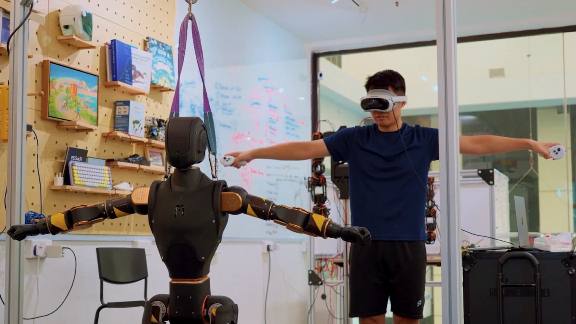 Asimov 1 supported by a gantry beside an operator wearing a VR headset, both with arms extended.
