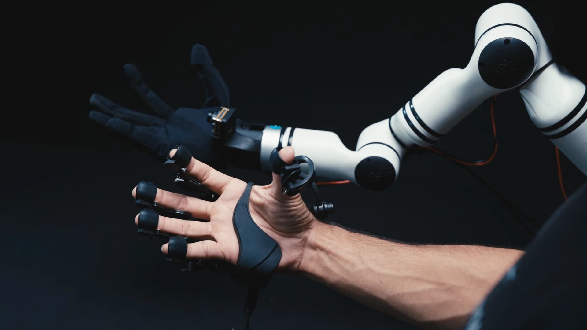 An operator wearing the Aero UMI hand capture device holds an open palm beside an Aero Hand mounted on a white robotic arm.