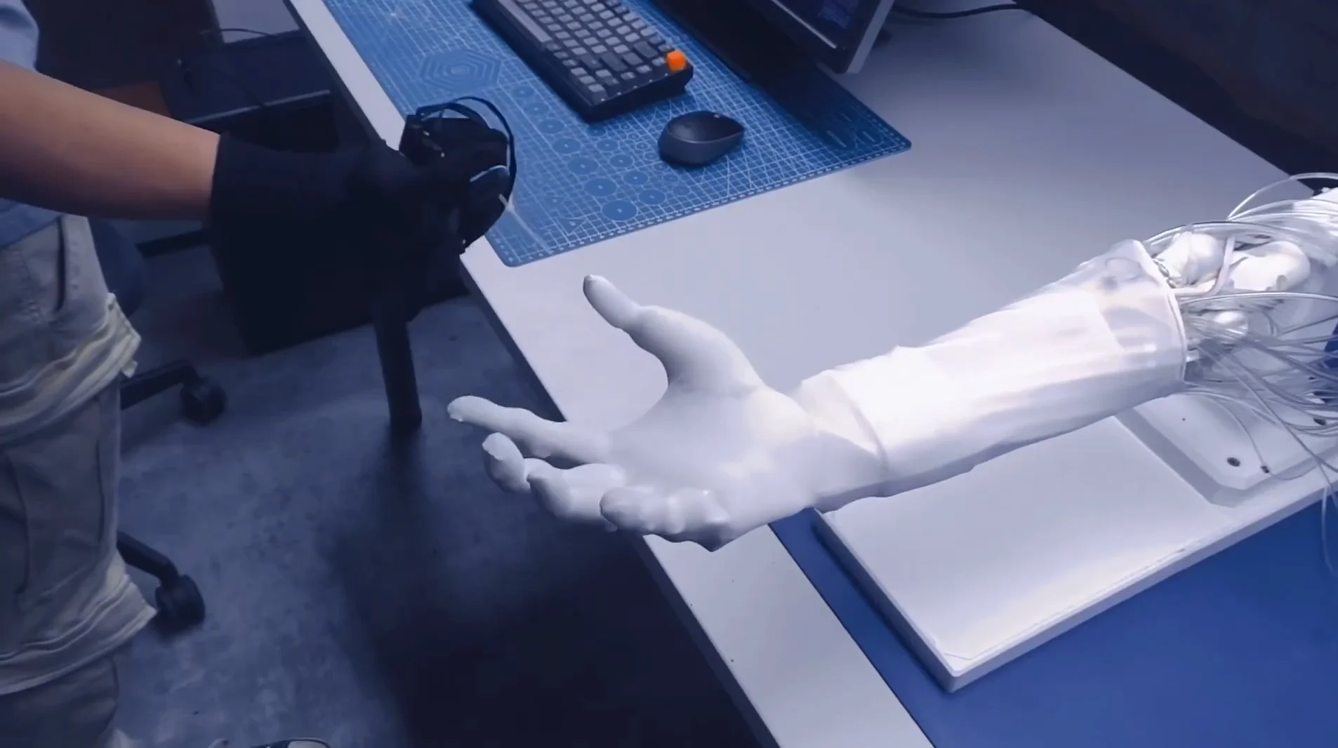 Clone robotic hand mounted on a desk shown being teleoperated