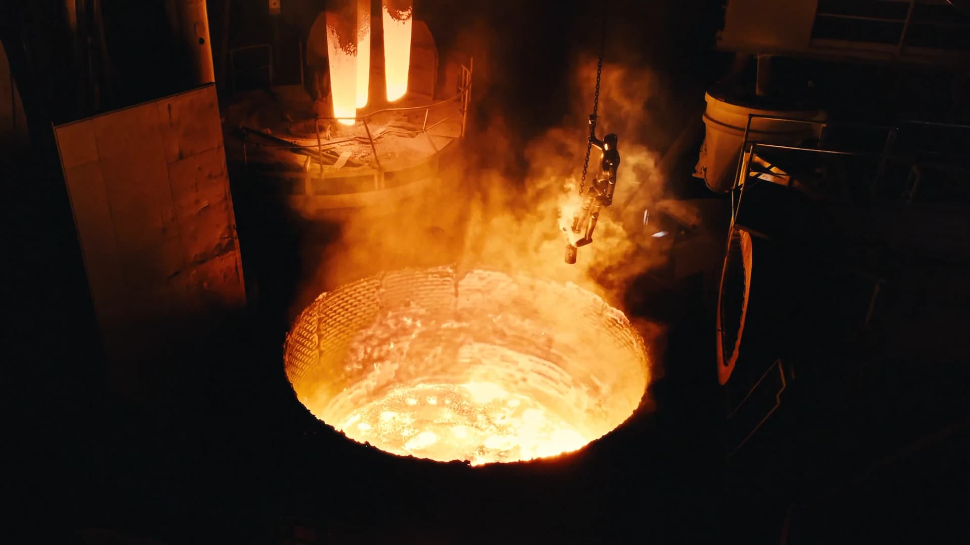Figure 02 hangs from a chain above a glowing furnace in Figure’s decommissioning film.