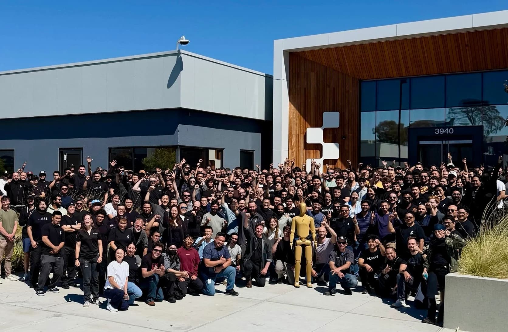 The Figure team gathered outside their building, posing with a special golden-colored Figure 03 robot standing front and center.