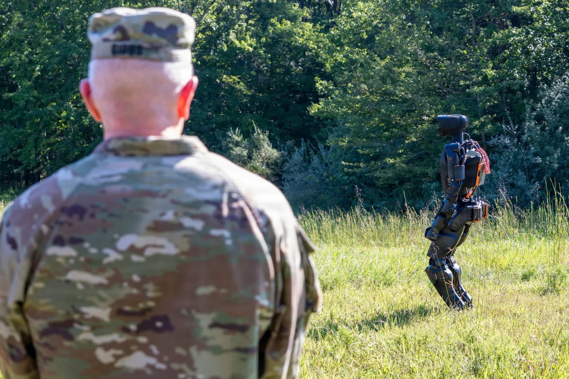 A uniformed observer watches IHMC’s Alex humanoid robot outdoors at the xTechHumanoid finals.