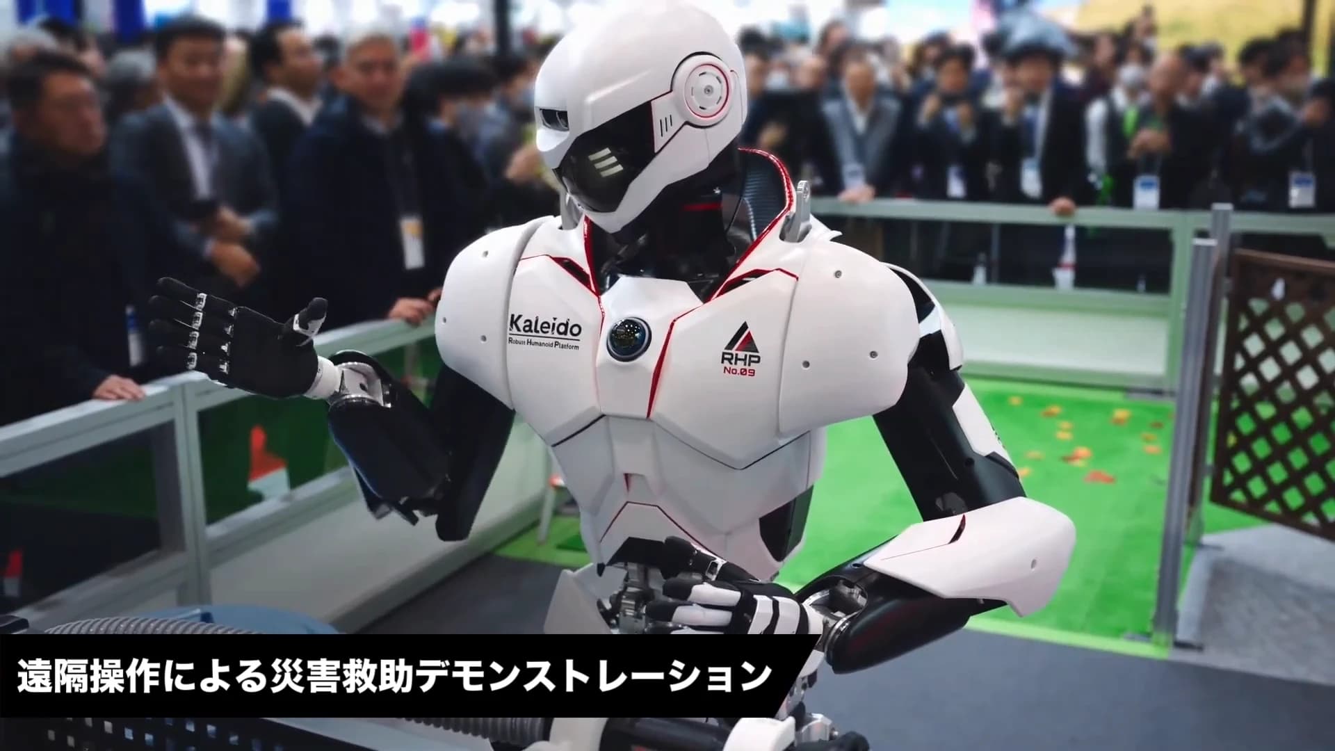Kawasaki’s white-and-black Kaleido 9 humanoid during an iREX 2025 demonstration, with an on-screen banner identifying remote-operated disaster rescue.
