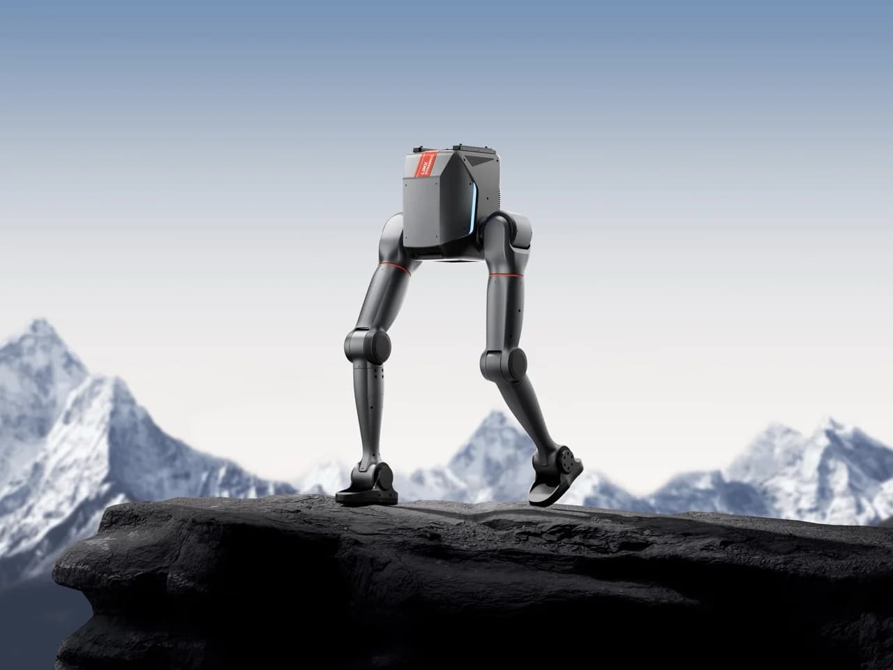 The lower body of the TRON 2 robot in its bipedal configuration, featuring articulated legs with flat feet standing on a rocky cliff edge against a mountain backdrop.