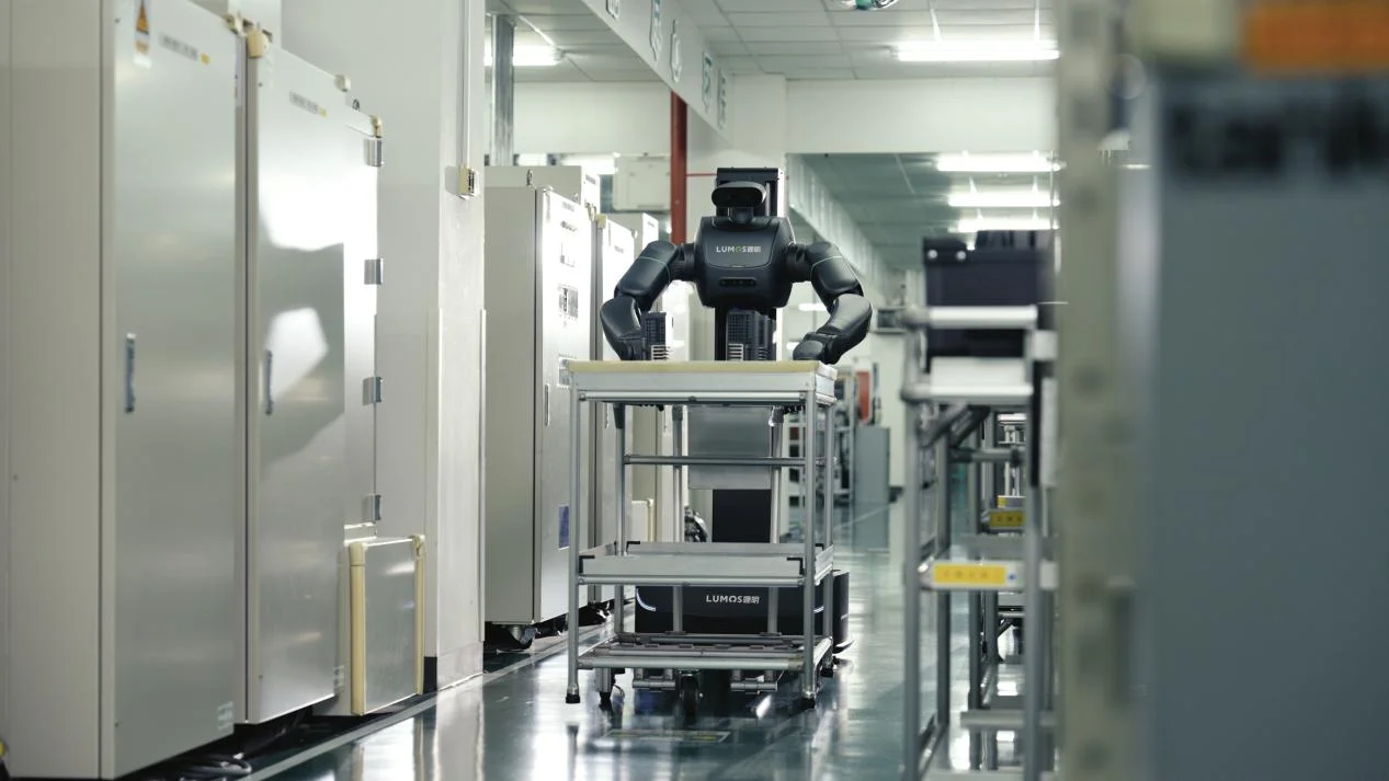 A Lumos MOS 2 robot maneuvering a multi-tier cart through a cleanroom factory environment.