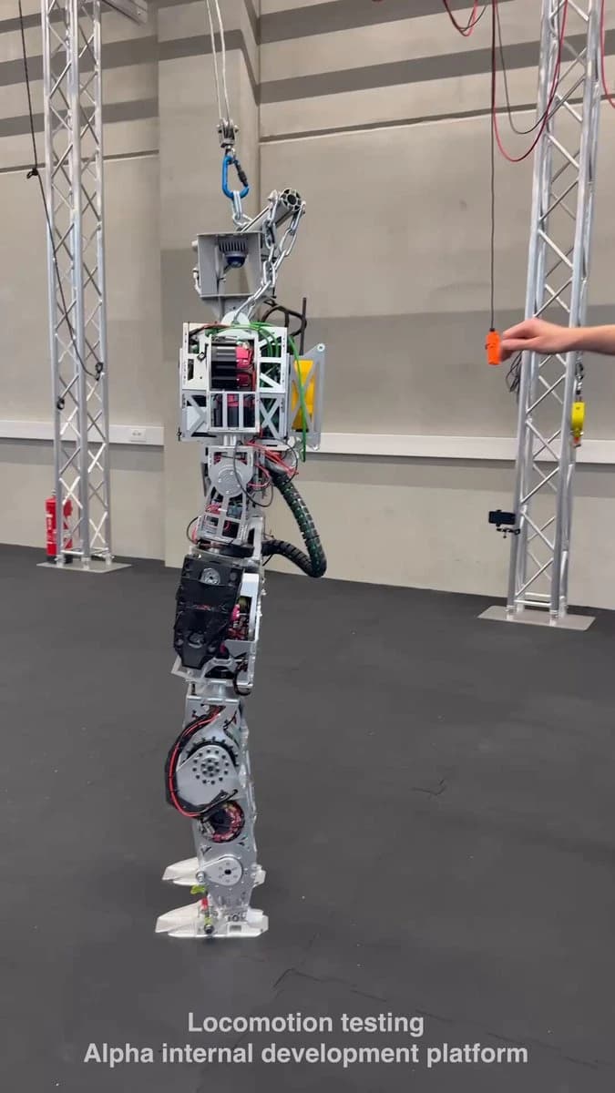 Side view of the Kyle humanoid development platform, with exposed wiring and a rectangular frame beneath an overhead testing rig.