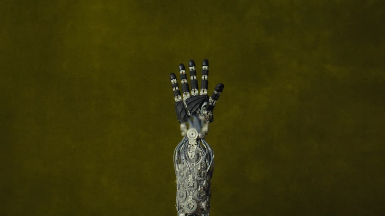 An exposed view of the NEO robotic arm against an olive green background, revealing the complex array of motors and tendon cables housed within the forearm that drive the black segmented fingers.
