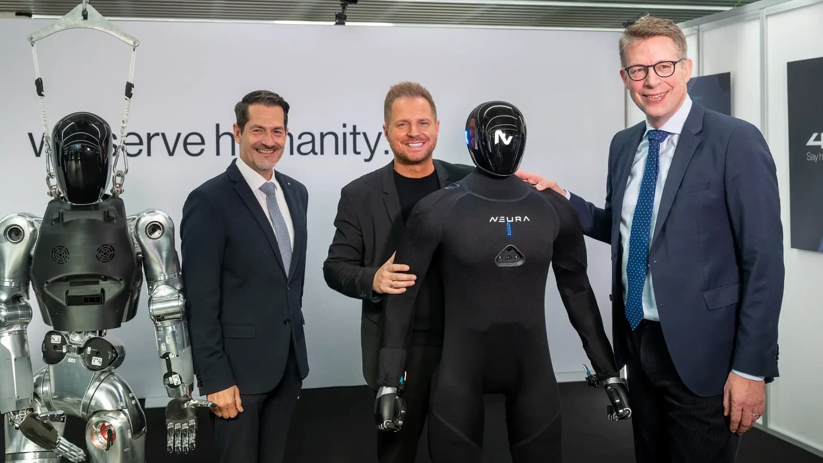 NEURA’s black textile-covered 4NE1 Gen 4 alongside another humanoid and attendees at the TUM RoboGym opening.