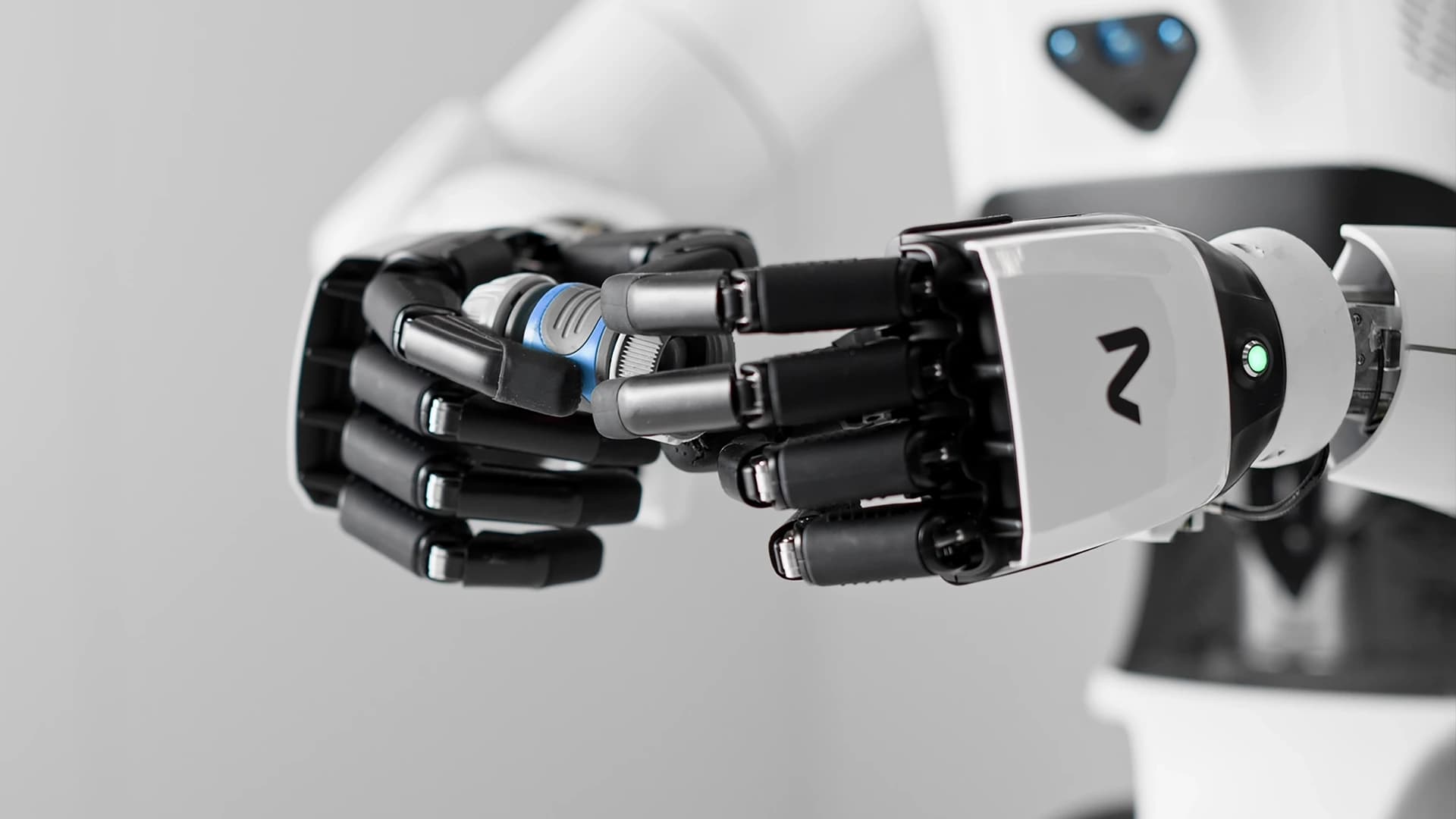 Close-up of a NEURA robot’s hands manipulating a small mechanical component.