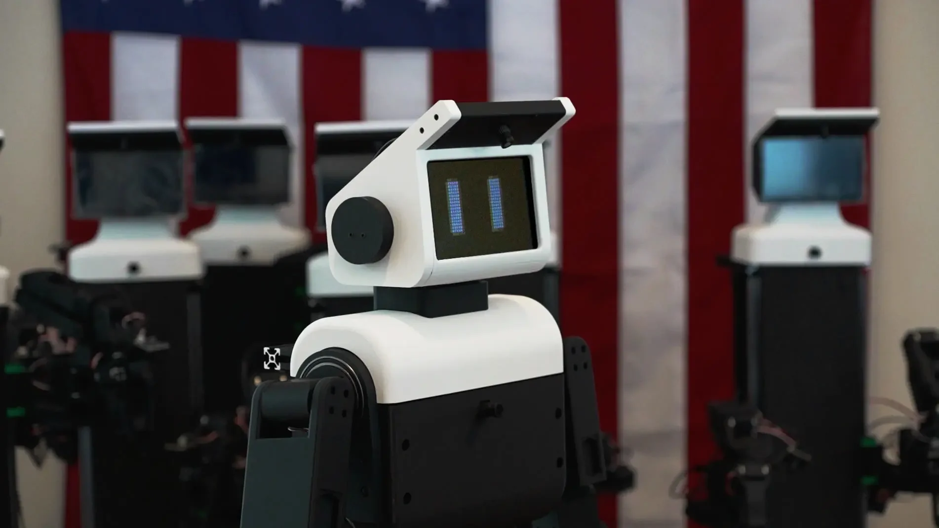 A row of Nori A3 mobile manipulators lined up in San Francisco with an American flag displayed in the background.