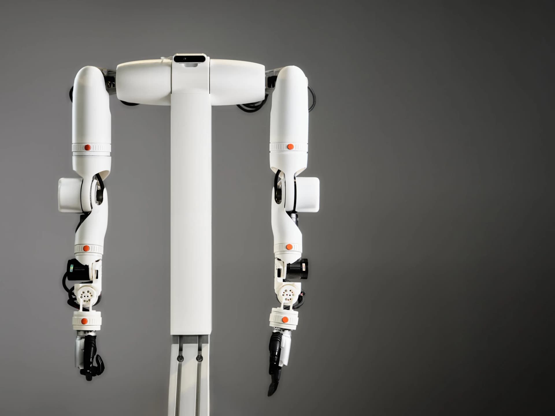 O-ID prototype with two white articulated arms, black grippers and orange buttons on modular connections.