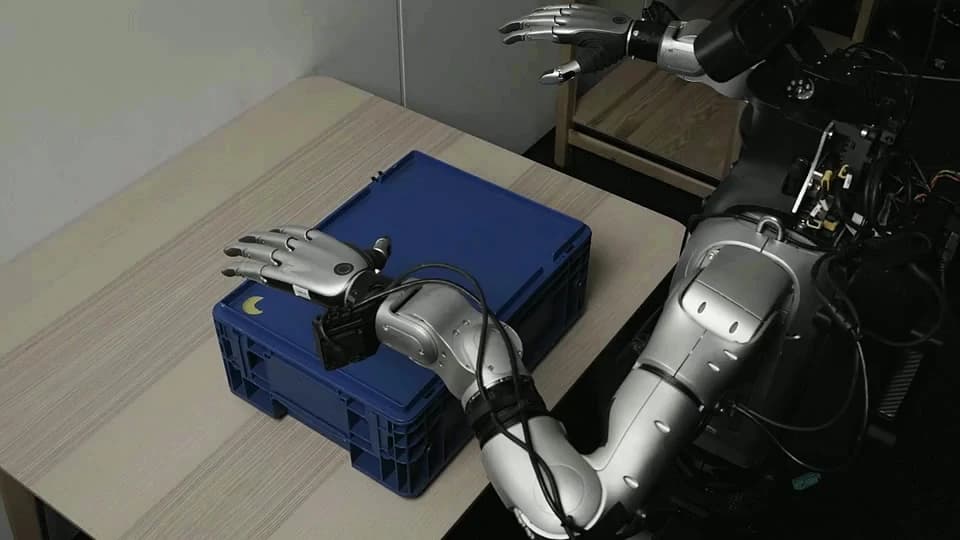 A humanoid in the Odyssey and Flexion demonstration reaches for the lid of a blue storage container.
