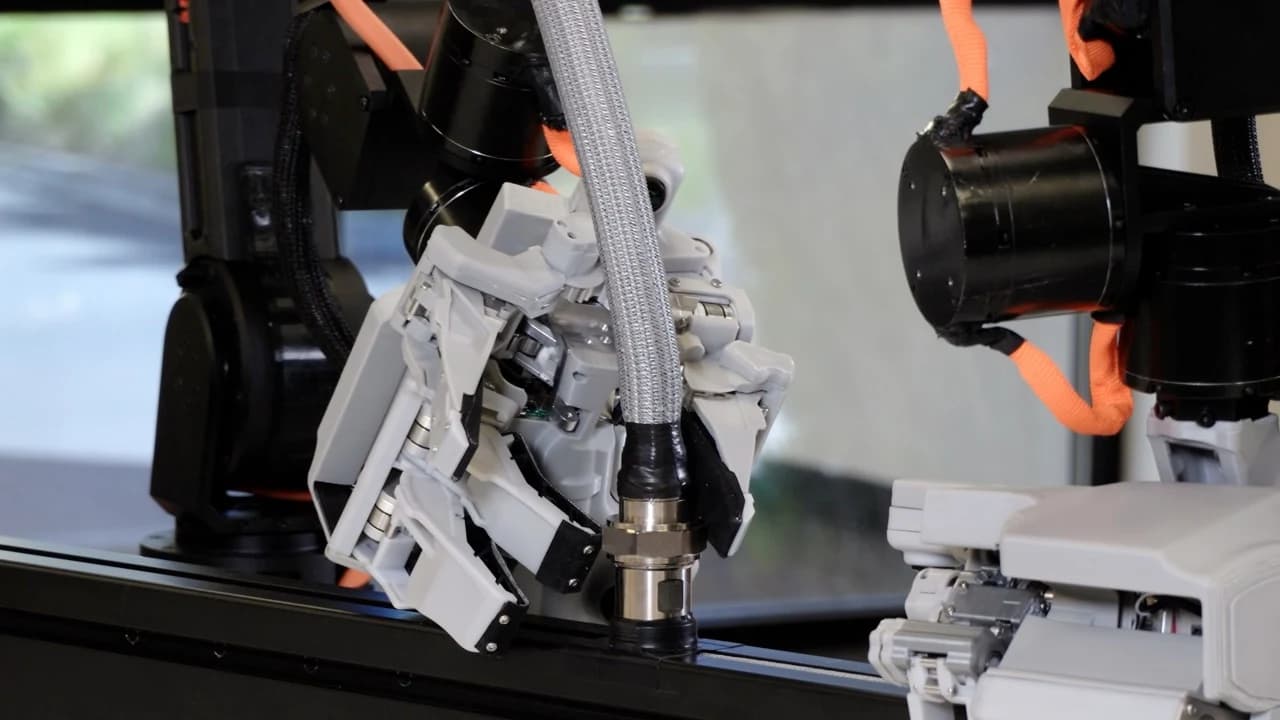 Close-up of articulated robotic fingers grasping a metal hose fitting in Reward AI’s unscrewing demonstration.