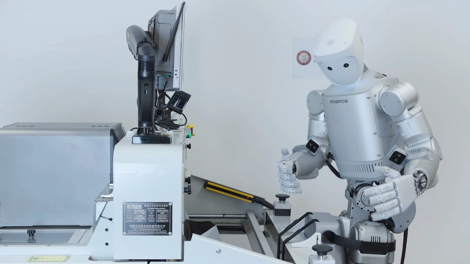 Robros IGRIS-C humanoid beside an automatic bagging machine during a demonstration.
