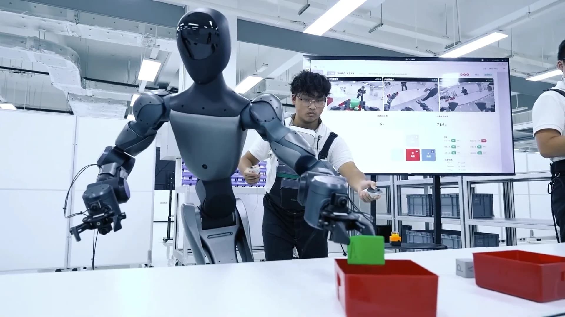 A humanoid robot handling a green block beside red trays, with an operator holding controllers behind it at Schaeffler’s Taicang facility.
