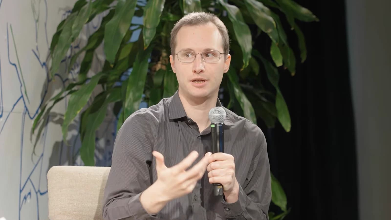 Sergey Levine holding a microphone during his South Park Commons interview about robotics and Physical Intelligence.