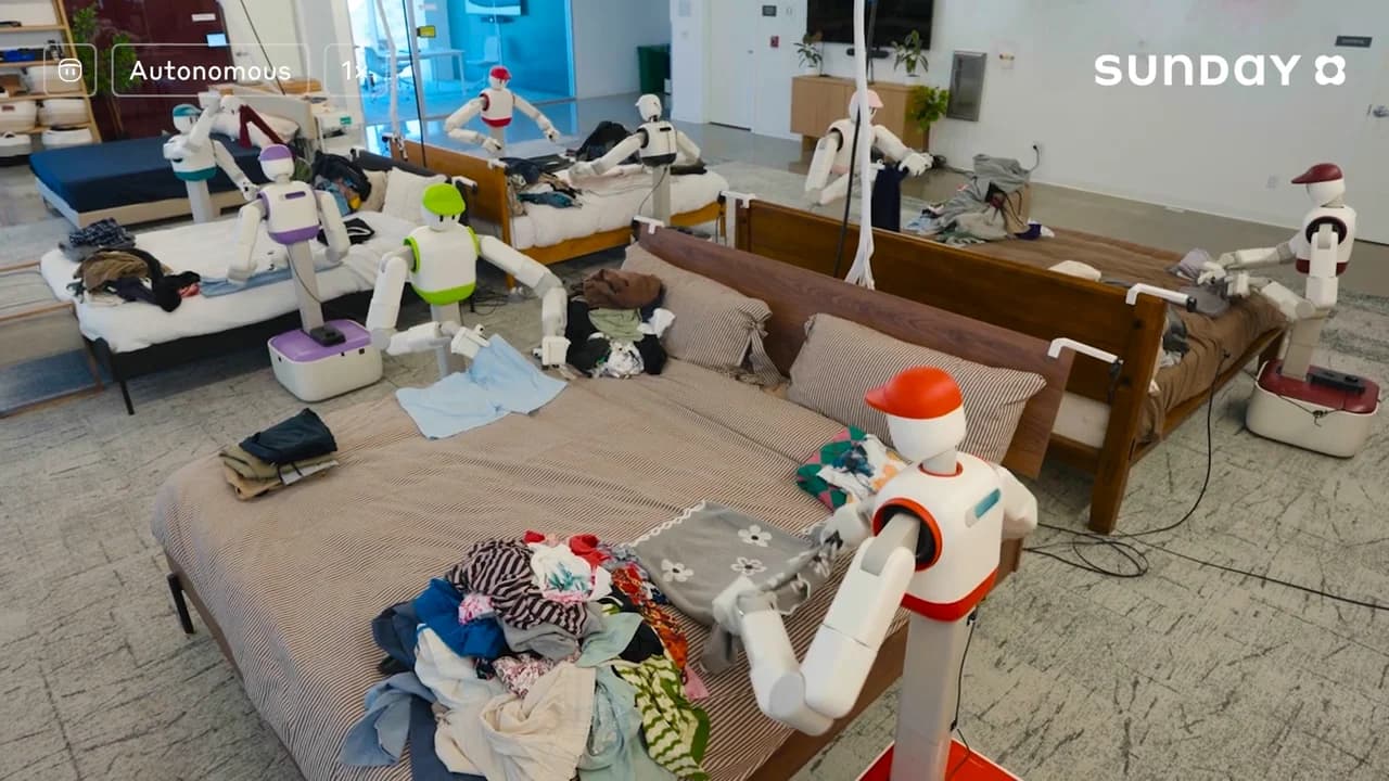 An overhead wide shot of Sunday Robotics' testing facility featuring several Memo robots folding laundry on beds simultaneously.