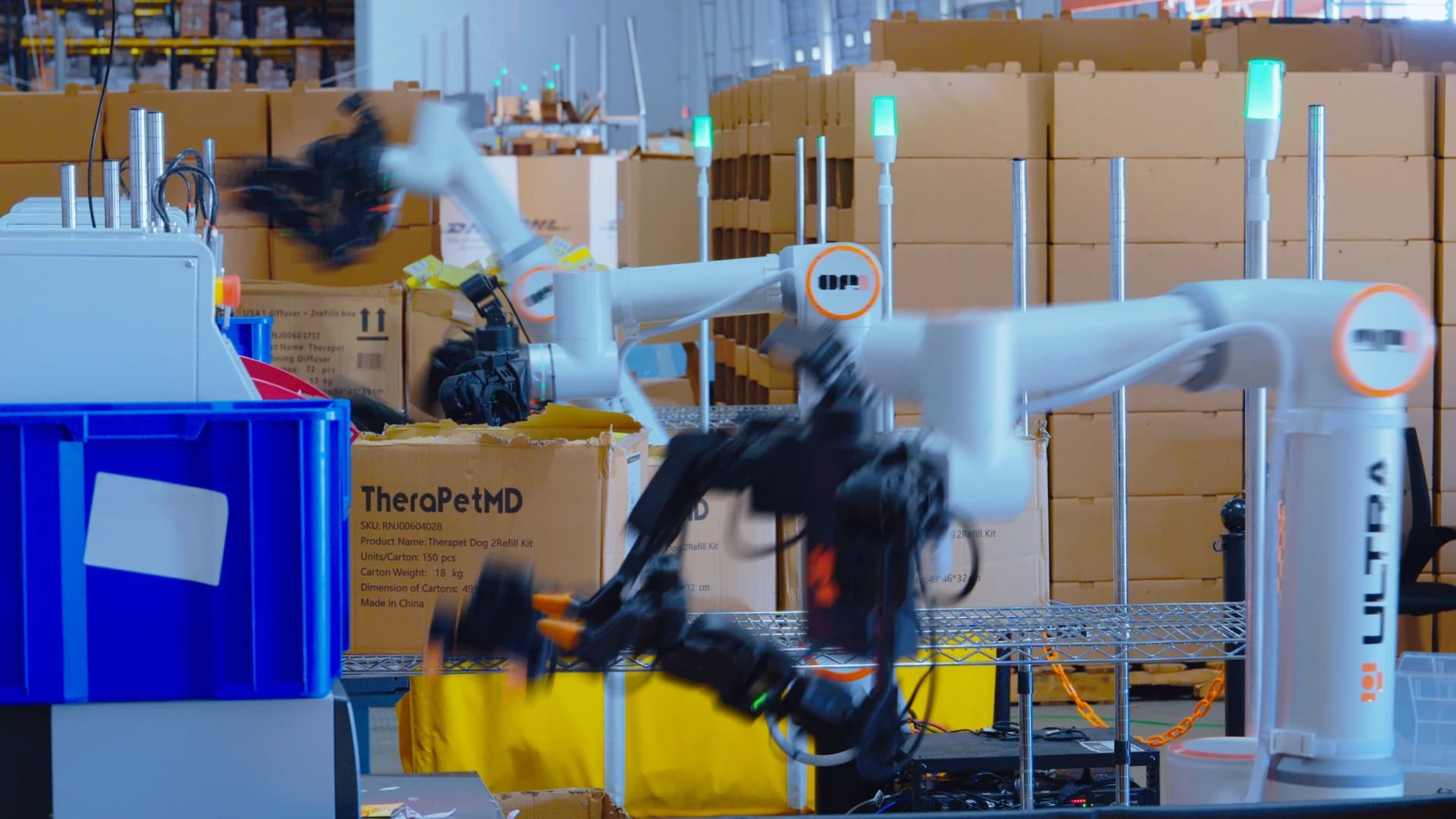 Ultra OP1 robots operating at warehouse workstations surrounded by cartons and a blue tote.