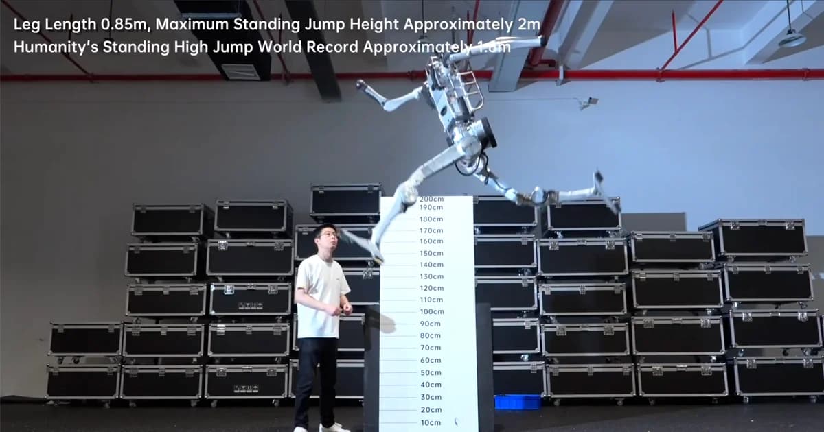 A silver and black humanoid robot captured mid-flight during a massive standing high jump. A man in a white t-shirt stands below looking up at the machine, next to a white measurement board peaking at 200cm. The background features stacks of black flight cases and a red ceiling pipe. Text on the screen reads: "Leg Length 0.85m, Maximum Standing Jump Height Approximately 2m. Humanity's Standing High Jump World Record Approximately 1.6m".