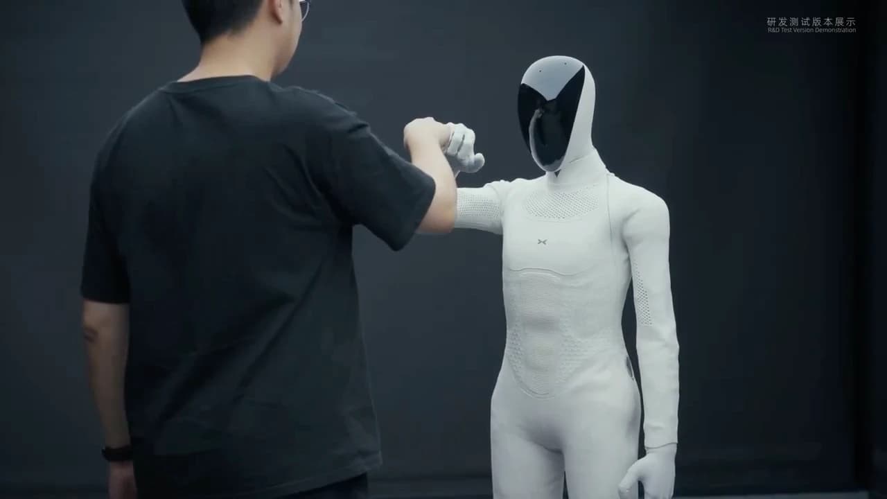 XPENG IRON exchanging a fist bump with a tester, with an R&D test-version label visible.